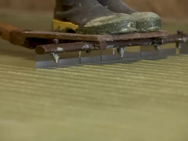A hand-pulled blade cutting the set soap into bars